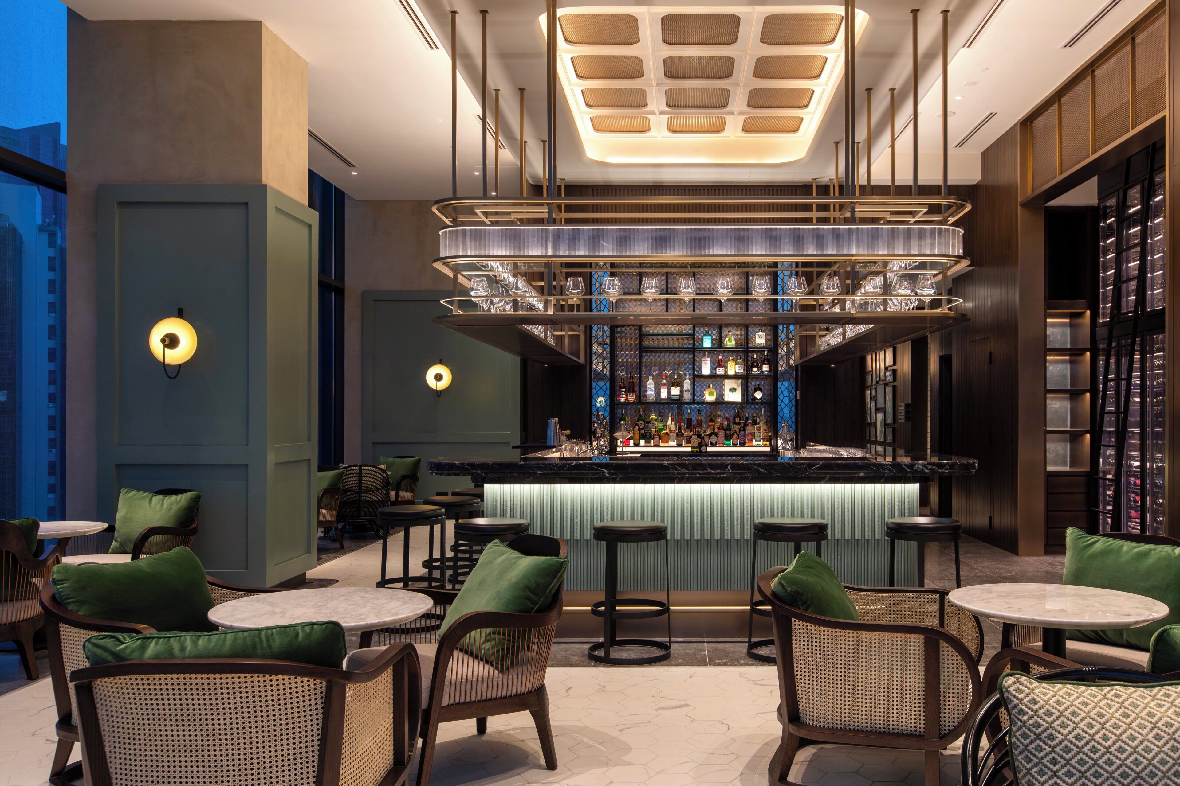 A bar area with a modern design, featuring a bar counter, stools, and a variety of bottles.
