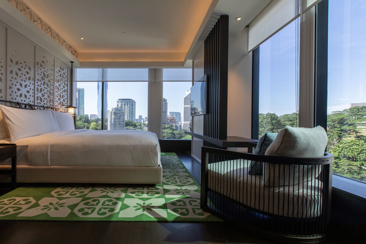 Une chambre d’hôtel moderne dotée d’un grand lit, offrant une vue sur la ville et comprenant un balcon avec une chaise.