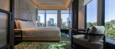 Una habitación de hotel moderna con una cama grande, vistas a la ciudad y un balcón con una silla.