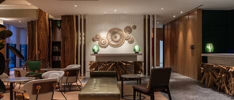 Un área de descanso moderna con un sofá, sillones, chimenea y estantería.