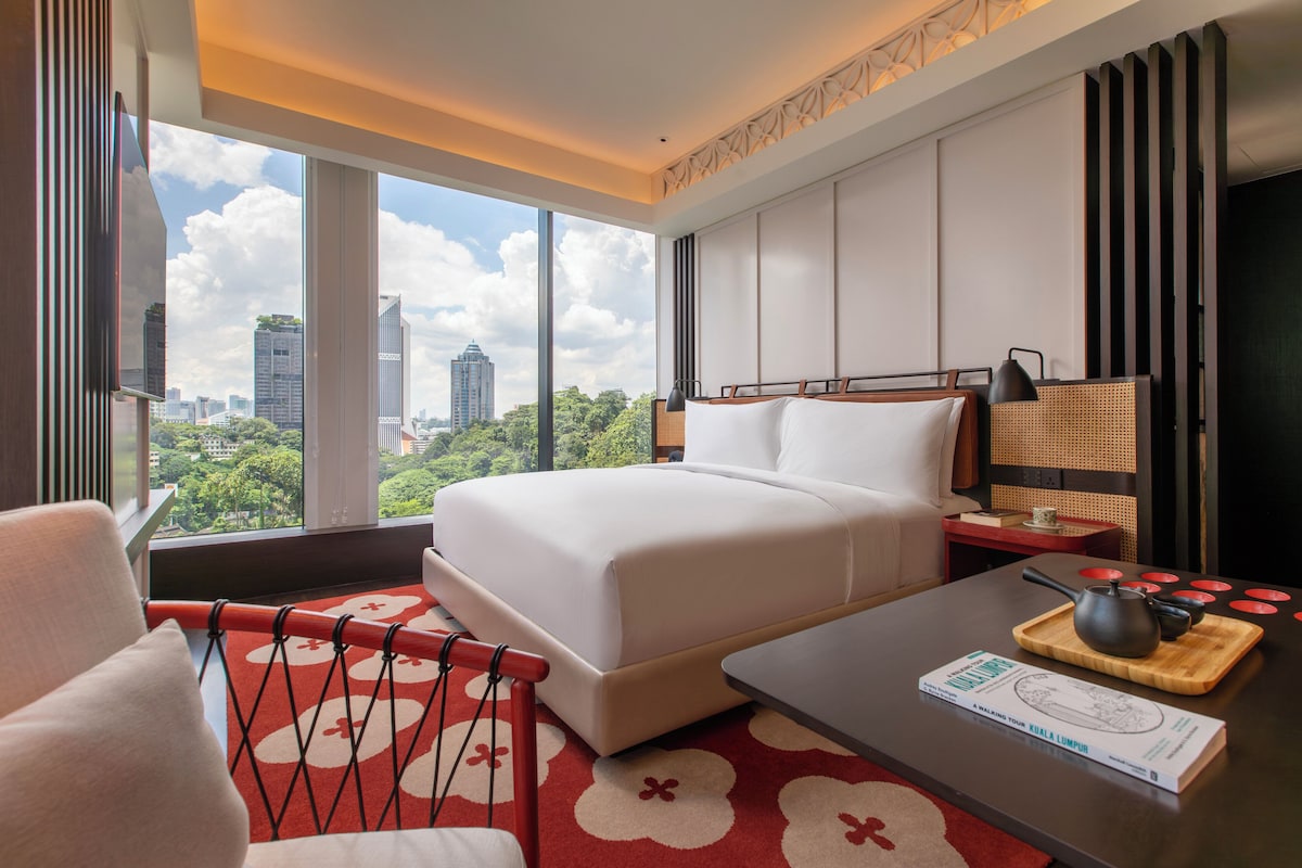 Une chambre d’hôtel avec un grand lit, un bureau, une chaise et une vue sur le paysage urbain.