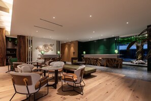 A modern living room with a wooden floor, a fireplace, and a seating area with chairs and a table. - Hotel Indigo Kuala Lumpur On The Park by IHG (Kuala Lumpur)