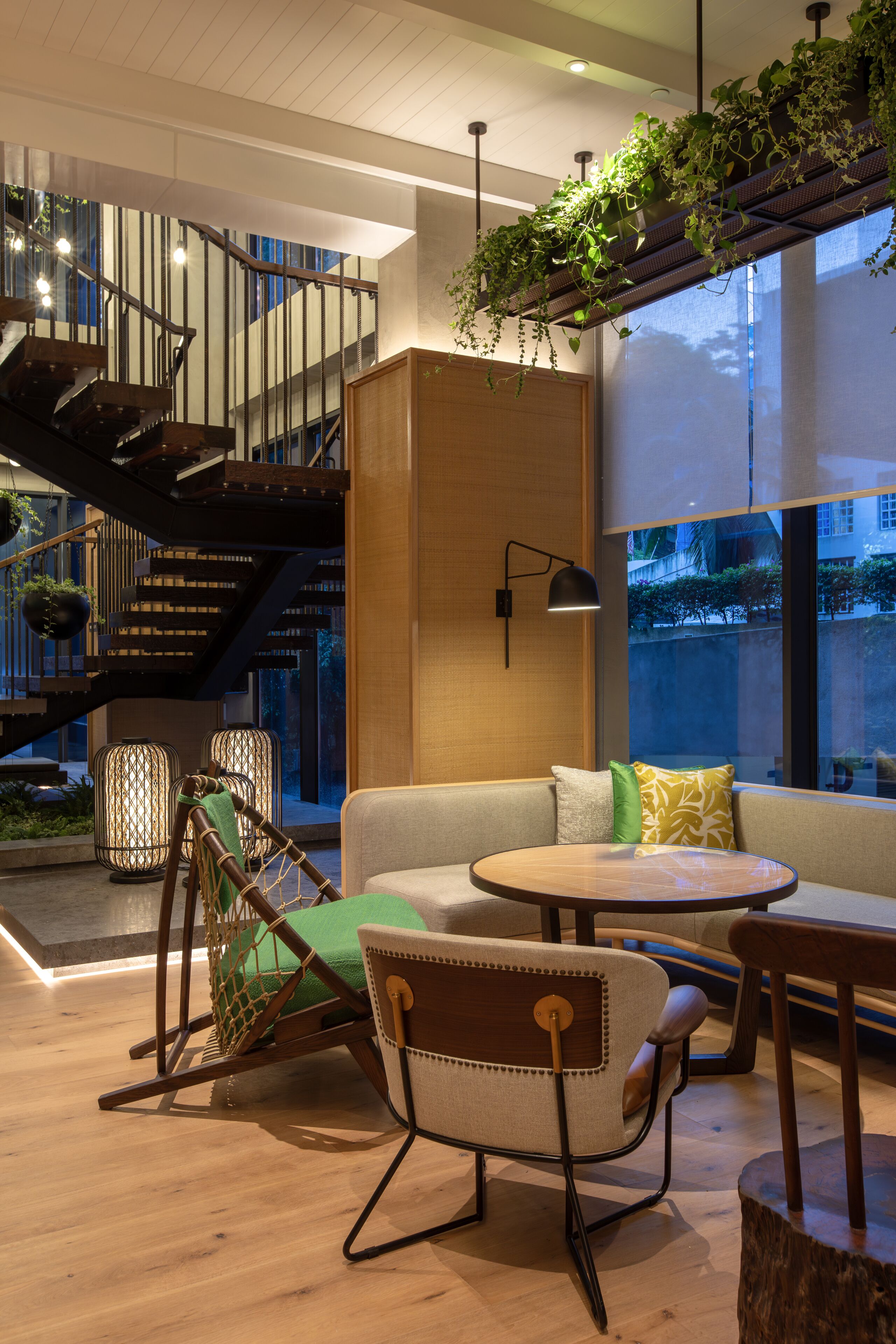 Un interior moderno con una escalera, zona de estar y ventanas amplias.