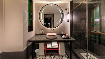Une salle de bain moderne avec un miroir rond, un lavabo rond et une cabine de douche en verre.