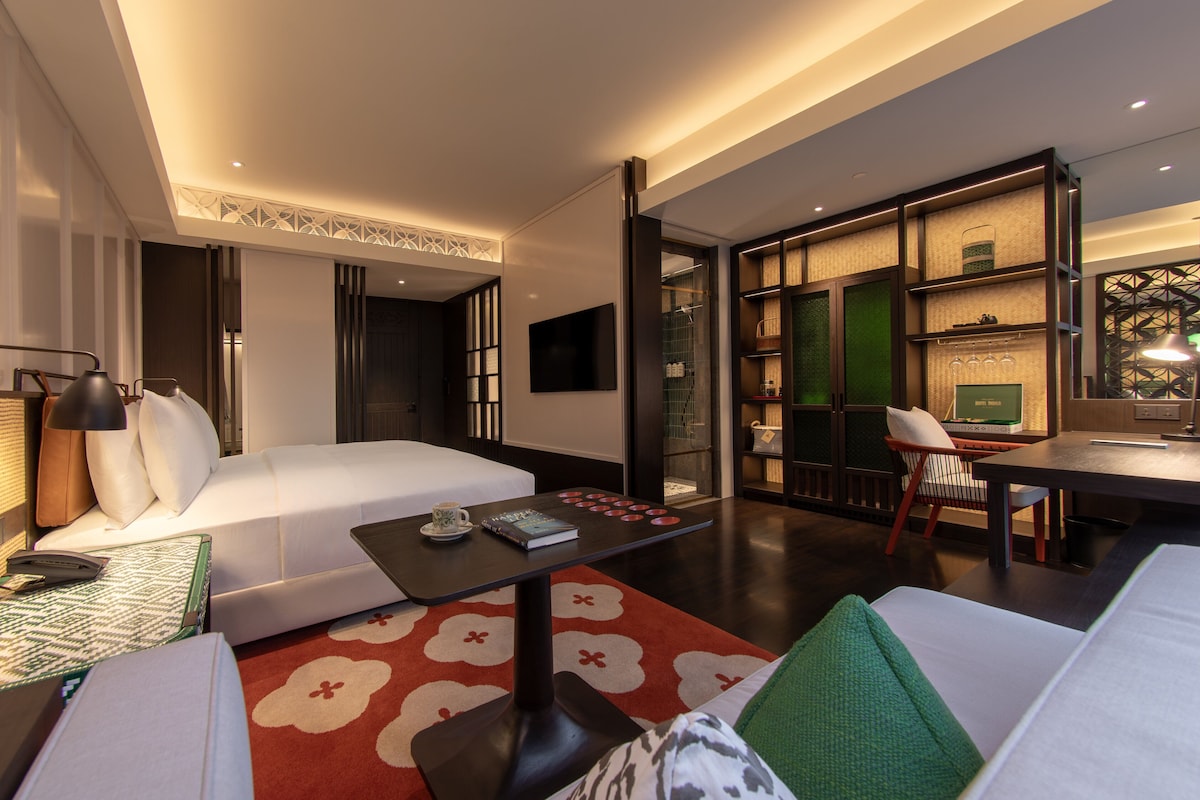 Une chambre d’hôtel moderne, dotée d’un grand lit, d’un bureau, d’une chaise et d’une bibliothèque.