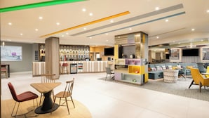 A modern hotel lobby with a reception desk, seating area, and bar. - Hampton by Hilton London Old Street (London)