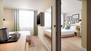 A hotel room with a bed, a desk with a kettle, a TV, and a window with curtains. - Hampton by Hilton London Old Street (London)