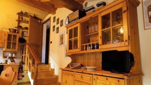 A wooden staircase leading to a kitchen with cabinets, a television, and various kitchen items. - [Apartment in the Romantic Courtyard] Lake Lugano (Brusimpiano)