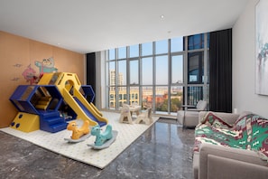 A modern living room with a play area, large windows, and a city view. - Holiday Inn TongXiang by IHG (Jiaxing)