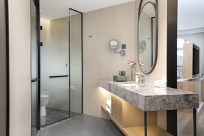Une salle de bain moderne avec une douche à parois de verre, un meuble-lavabo en marbre et un grand miroir.