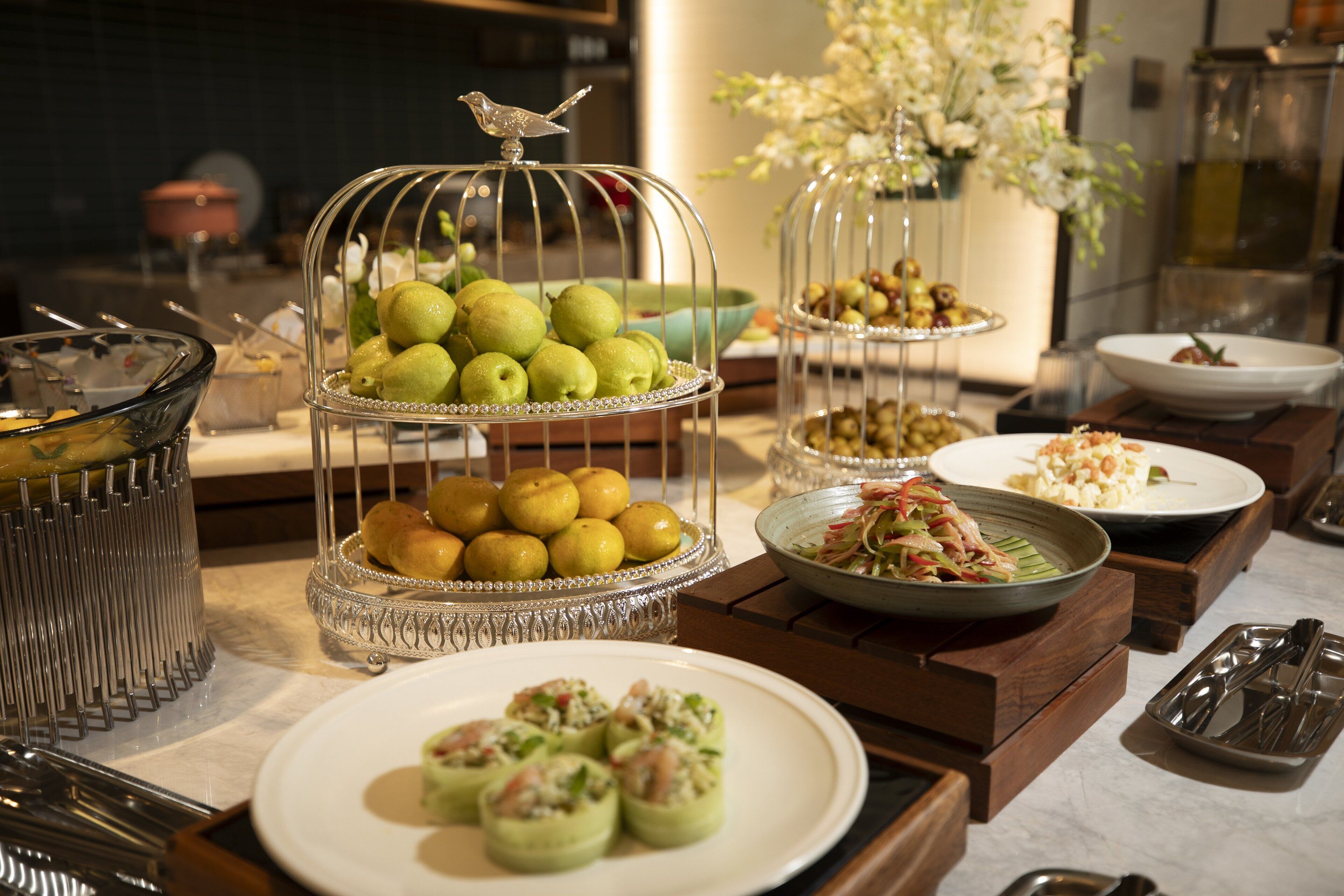 A buffet table with various dishes, including a fruit display and a plate of appetizers.