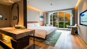 A modern hotel room with a large bed, a sitting area with a table, a large window with a city view, and a bathroom with a marble countertop. - Holiday Inn TongXiang by IHG (Jiaxing)
