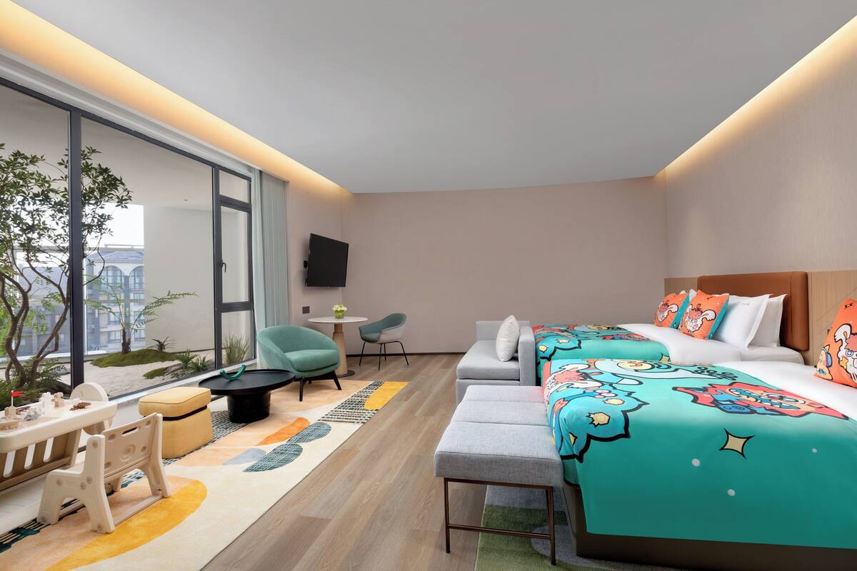 Una habitación de hotel moderna con una cama grande, un sofá, un escritorio y vistas a la ciudad.
