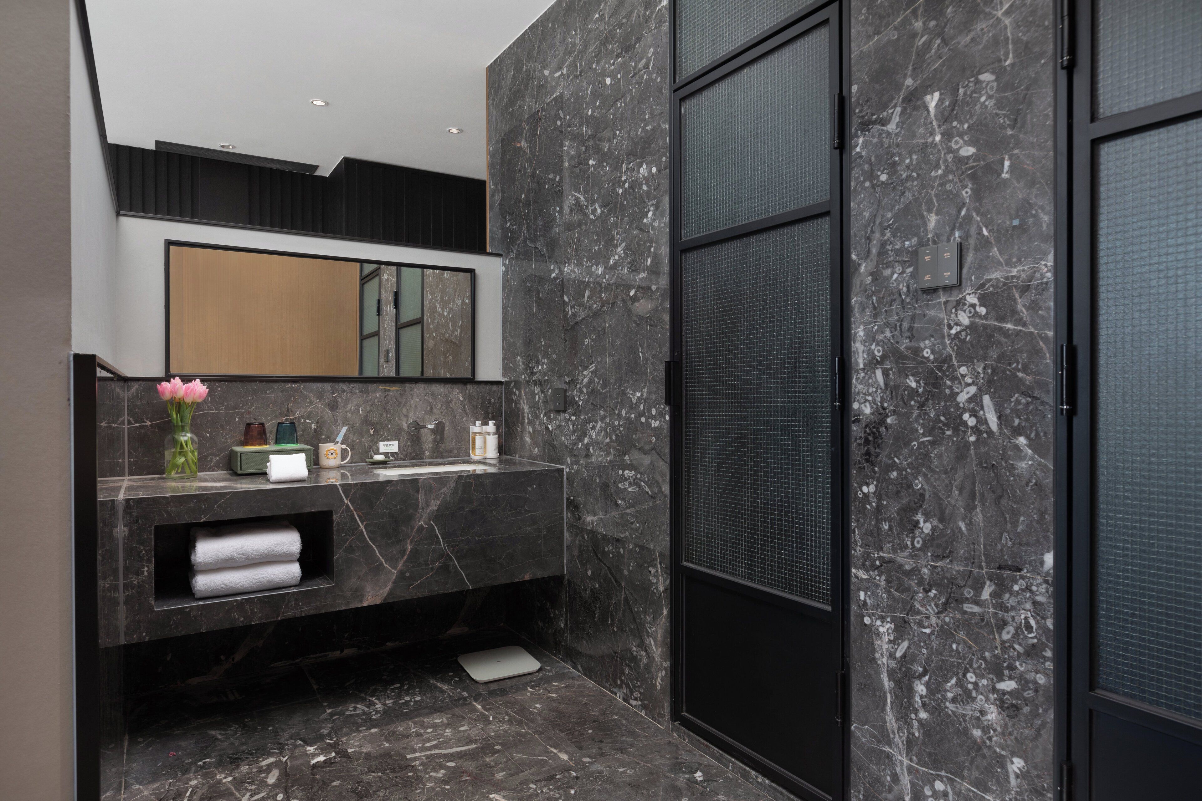 Un bagno moderno con un vanità in marmo, uno specchio grande e un box doccia.