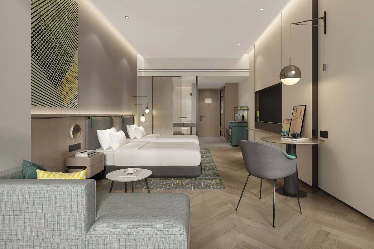 Una habitación de hotel moderna con cama, sofá, escritorio y televisión.
