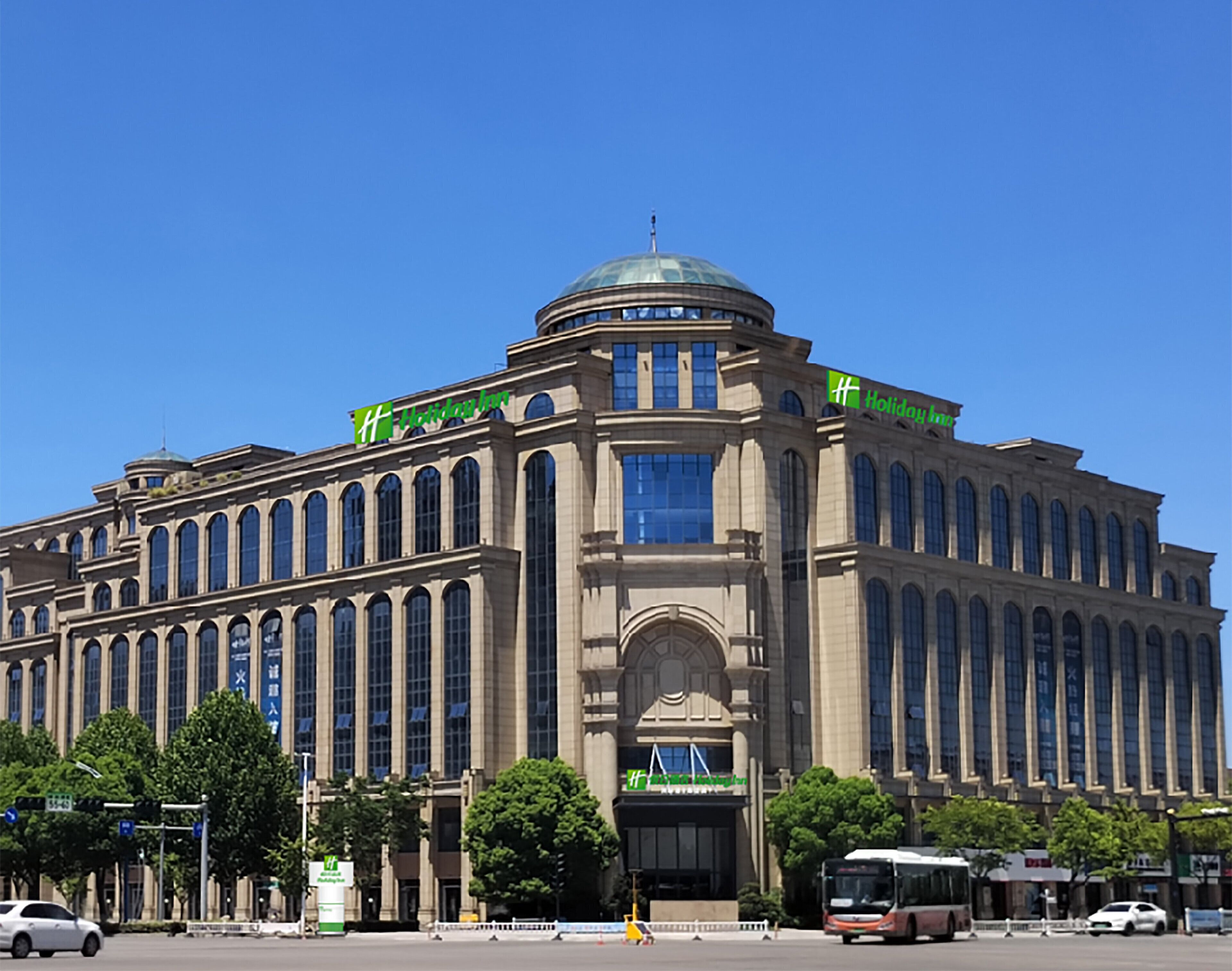 A large, historic building with a dome and arched windows, featuring the Holiday Inn logo.