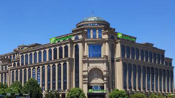A large, historic building with a dome and arched windows, featuring the Holiday Inn logo.