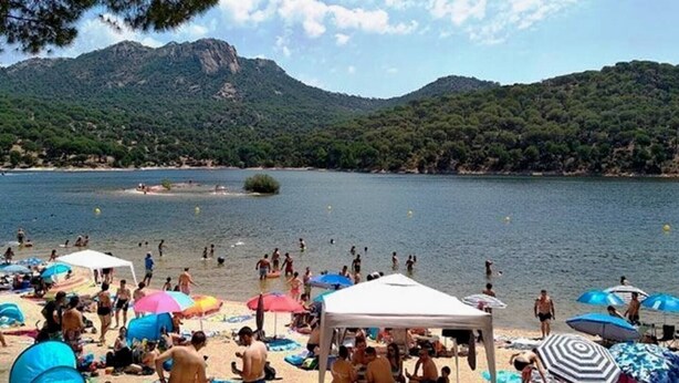 Une plage avec des gens, des parasols et une tente.