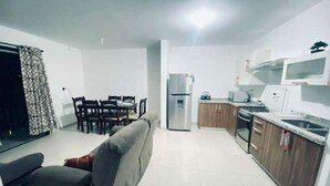 Een knus woongedeelte met eethoek, kitchenette en een bank.