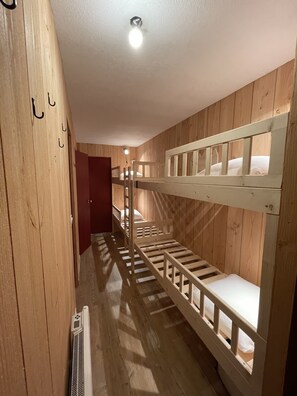 A bunk bed room with wooden walls and a ceiling light.