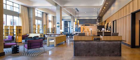 A spacious lobby with a reception desk, seating areas, and large windows.