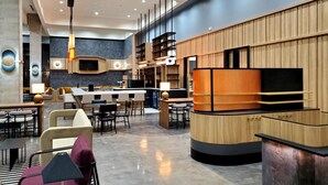 A modern hotel lobby with a bar area, seating arrangements, and a kitchen visible in the background. - Hyatt Place Nashville Green Hills (Nashville)