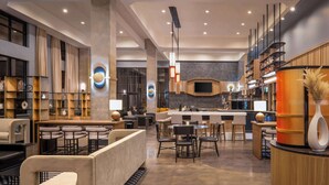 A modern hotel lobby with a bar area, seating arrangements, and a large screen. - Hyatt Place Nashville Green Hills (Nashville)