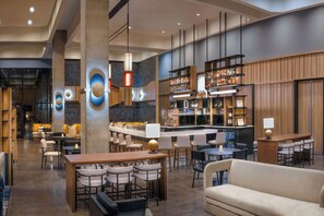 Eine moderne Bar mit einer Theke, Sitzgelegenheiten und einer Auswahl an Flaschen und Gläsern.