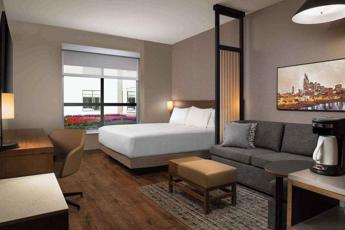 A hotel room with a bed, a sofa, a desk, and a coffee maker.
