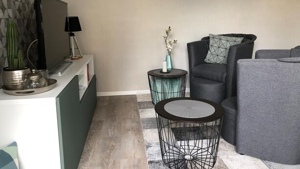 A modern living room with a grey sofa, a round coffee table, and a small side table with a vase.