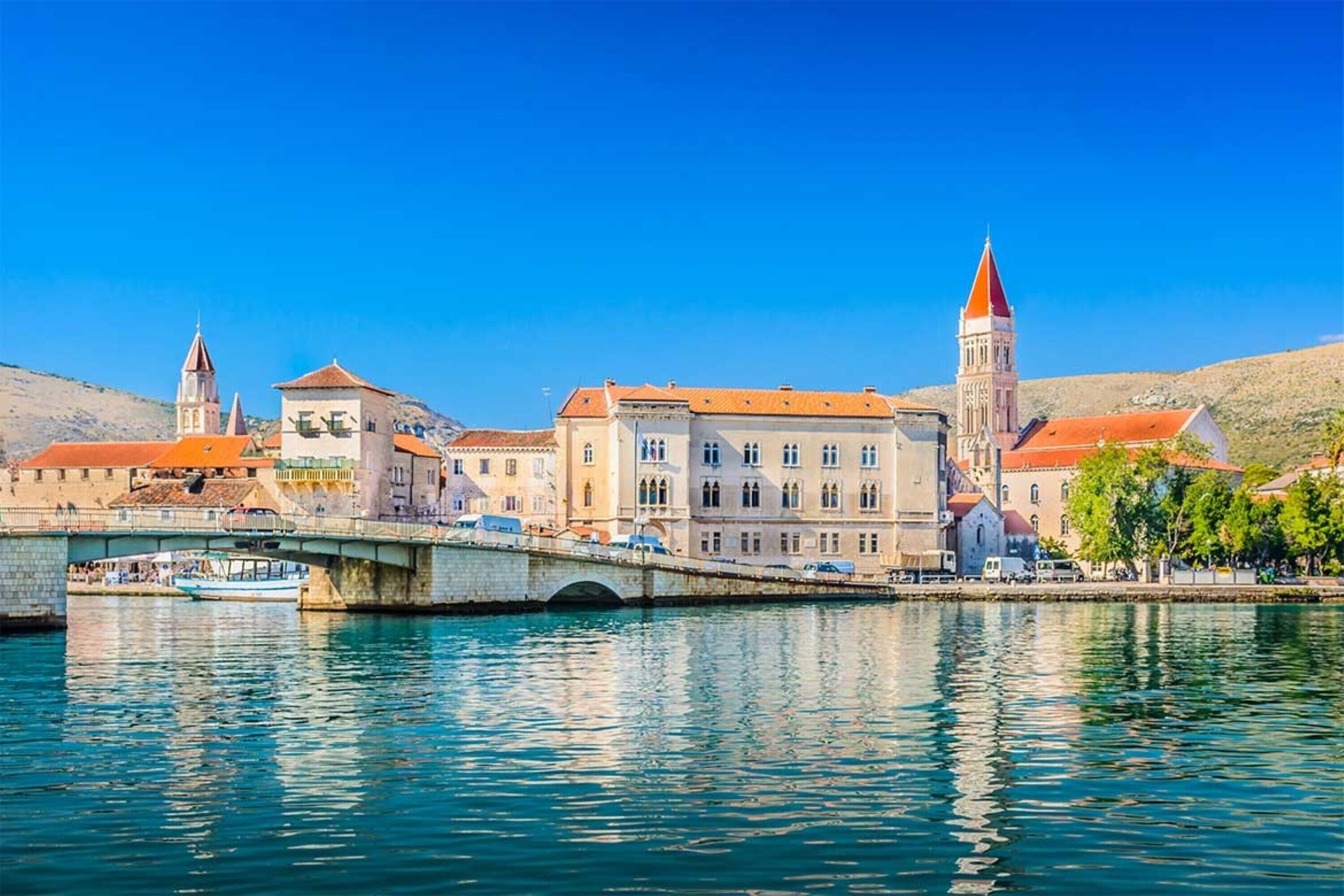 A historic town with a prominent bridge, waterfront buildings, and a tower.