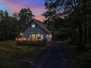 A two-story house with a deck, surrounded by trees, and a path leading to the entrance. - Warm Chalet in Emerald Lakes, Poconos! Lakes/Pools/Deck/Kayak/Fire pits/Grill (Long Pond)