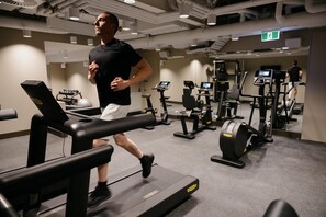 Une salle de sport équipée de tapis de course, de vélos d’exercice et d’appareils de musculation.