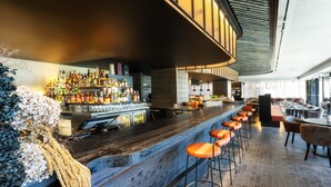 A bar area with a long counter, multiple stools, and a variety of bottles. - Intercontinental Auckland (Auckland)