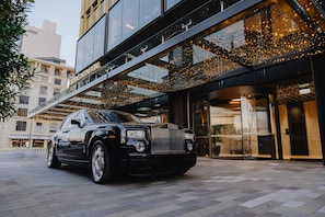 A black luxury car parked in front of a modern building with a glass facade and a sign reading 'INTERCONTINENTAL'.