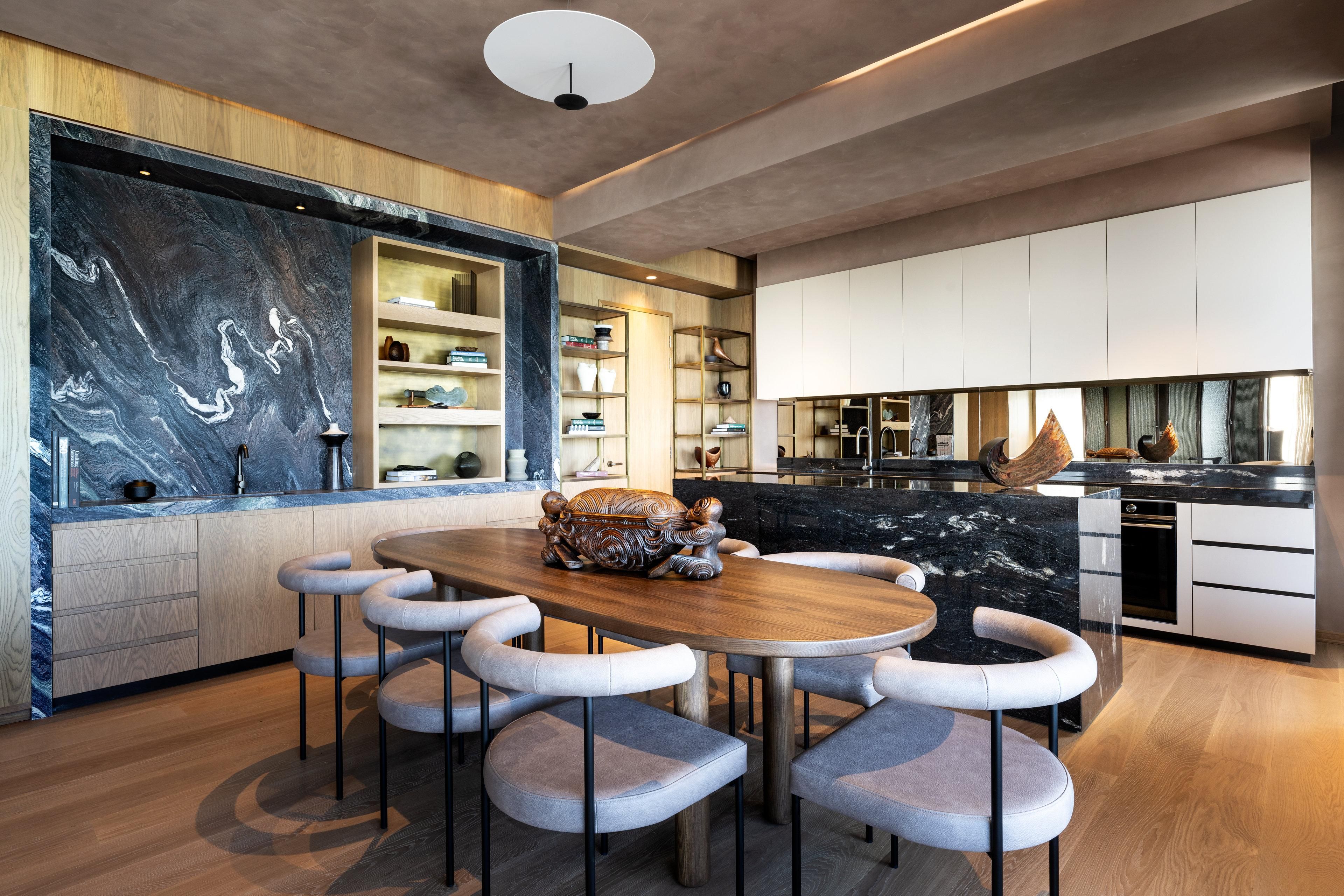 Una cocina moderna con salpicadero de mármol, armarios de madera y una isla central con taburetes de bar.