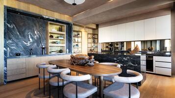 Una cocina moderna con salpicadero de mármol, armarios de madera y una isla central con taburetes de bar.