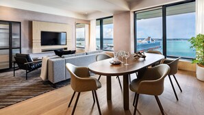 A modern living room with a large TV, a dining table with chairs, a sofa, and a view of the sea. - Intercontinental Auckland (Auckland)