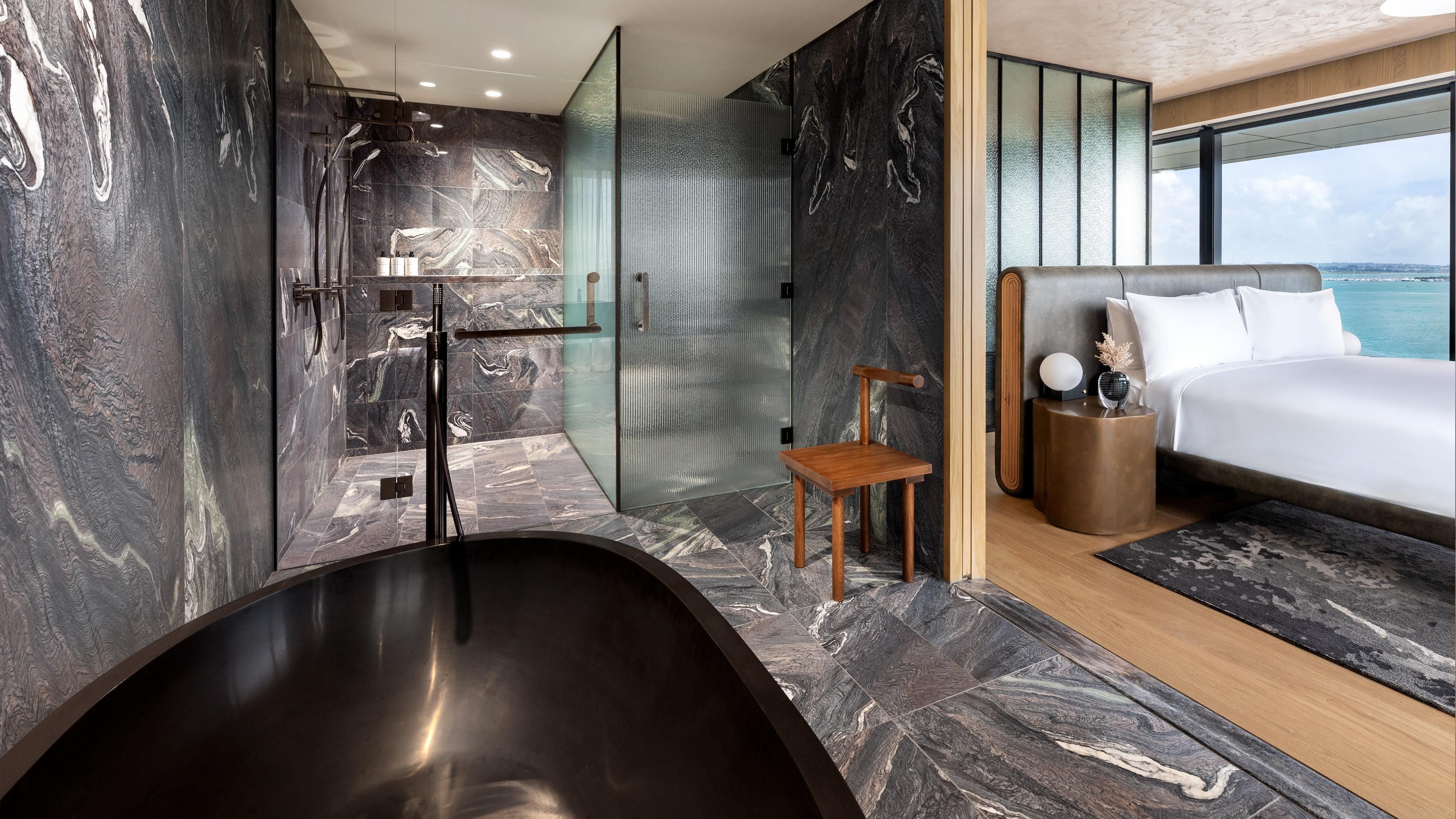 Ein modernes Badezimmer mit einer freistehenden Badewanne, einer Duschkabine aus Glas und einem Holzstuhl.