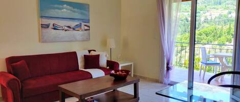 A living room with a red sofa, a glass coffee table, and a painting of boats on the wall.