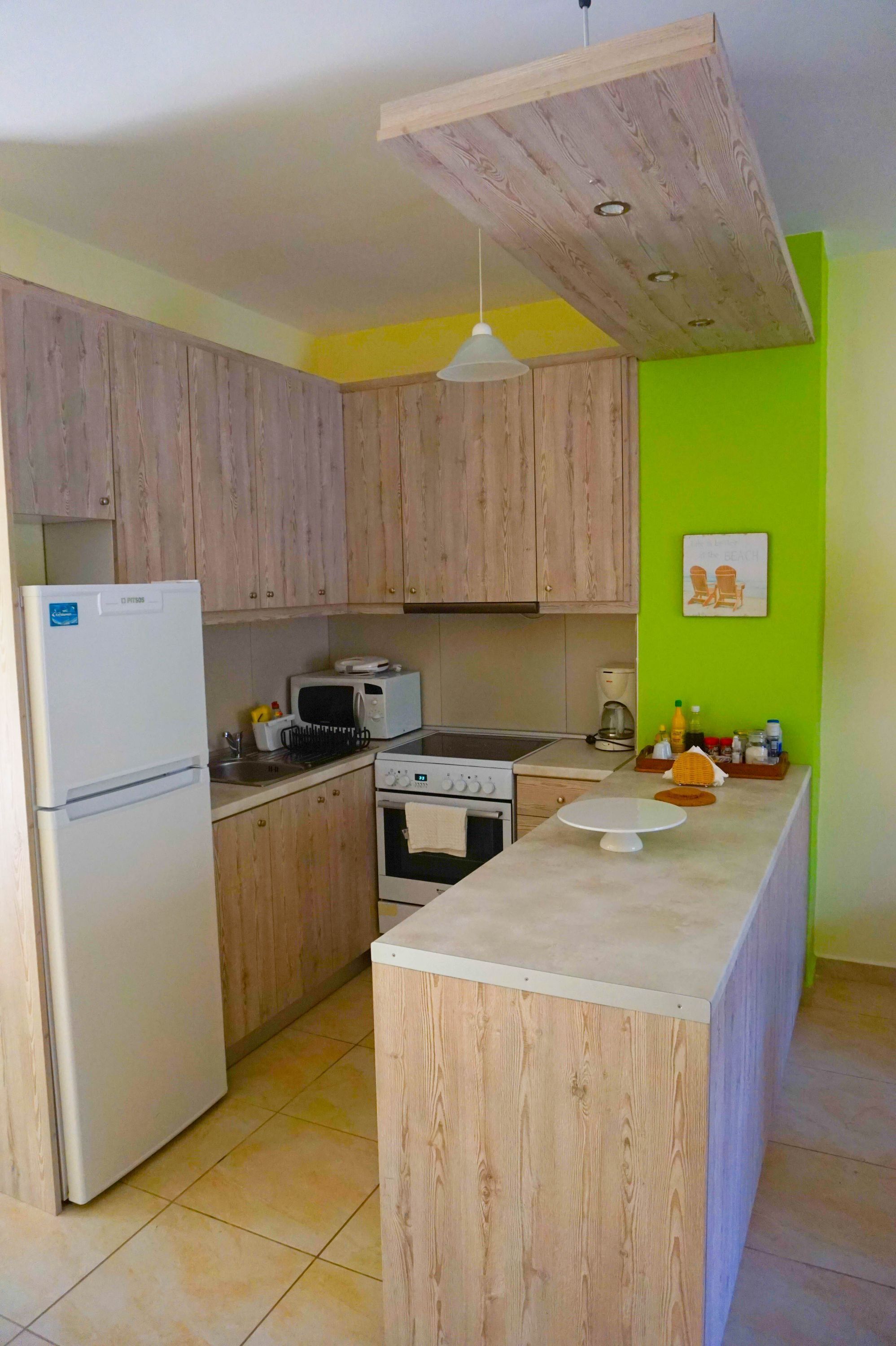 A kitchen with wooden cabinets, a refrigerator, a microwave, an oven, and a sink.