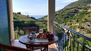Un balcon avec une table préparée pour le petit-déjeuner, offrant une vue sur un paysage montagneux.