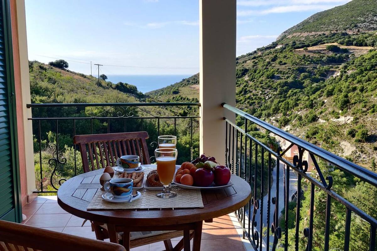 Ein Balkon mit Frühstückstisch, mit Blick auf eine gebirgige Landschaft.