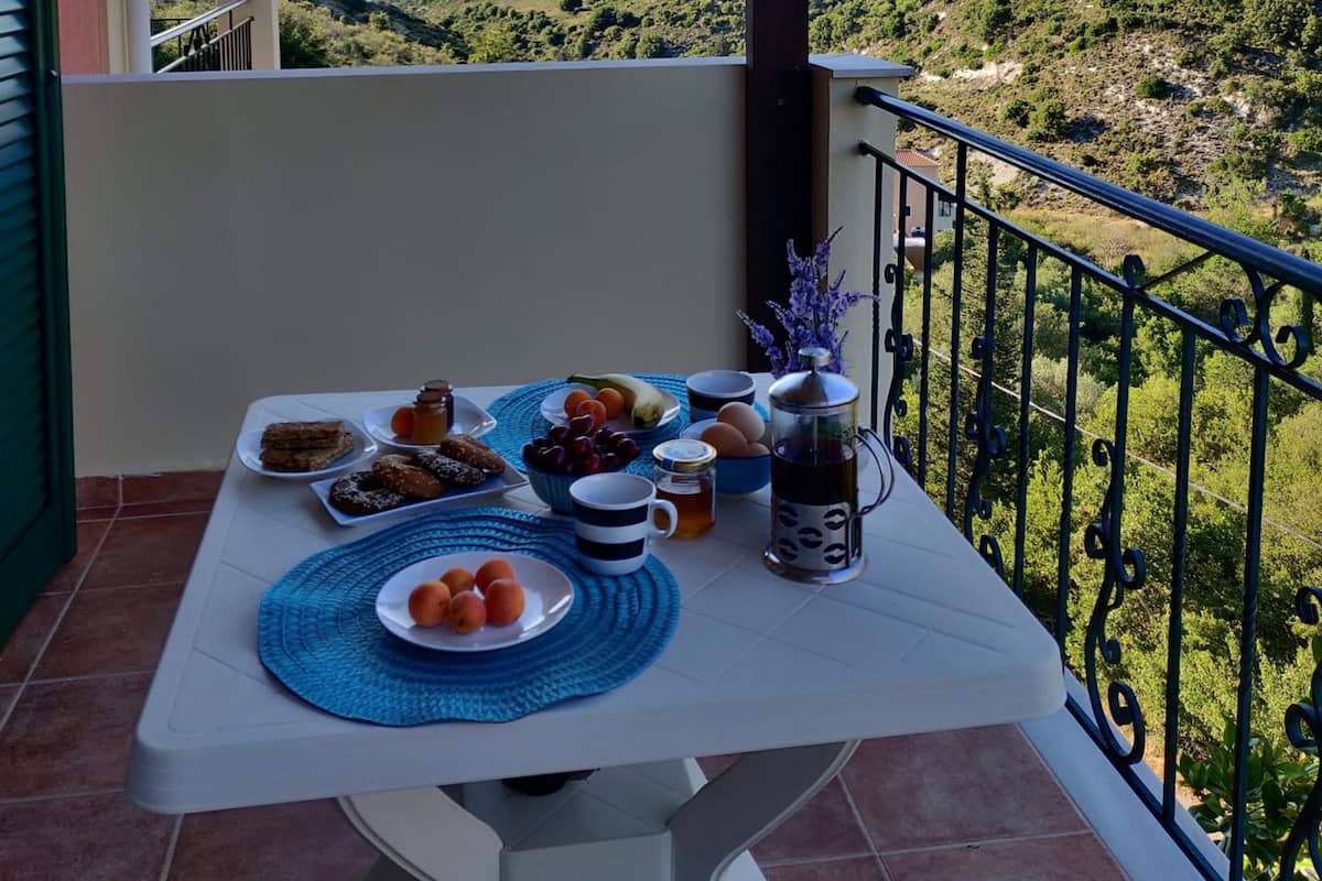 Ein Balkon mit Frühstückstisch, mit Blick auf eine schöne Hügellandschaft.