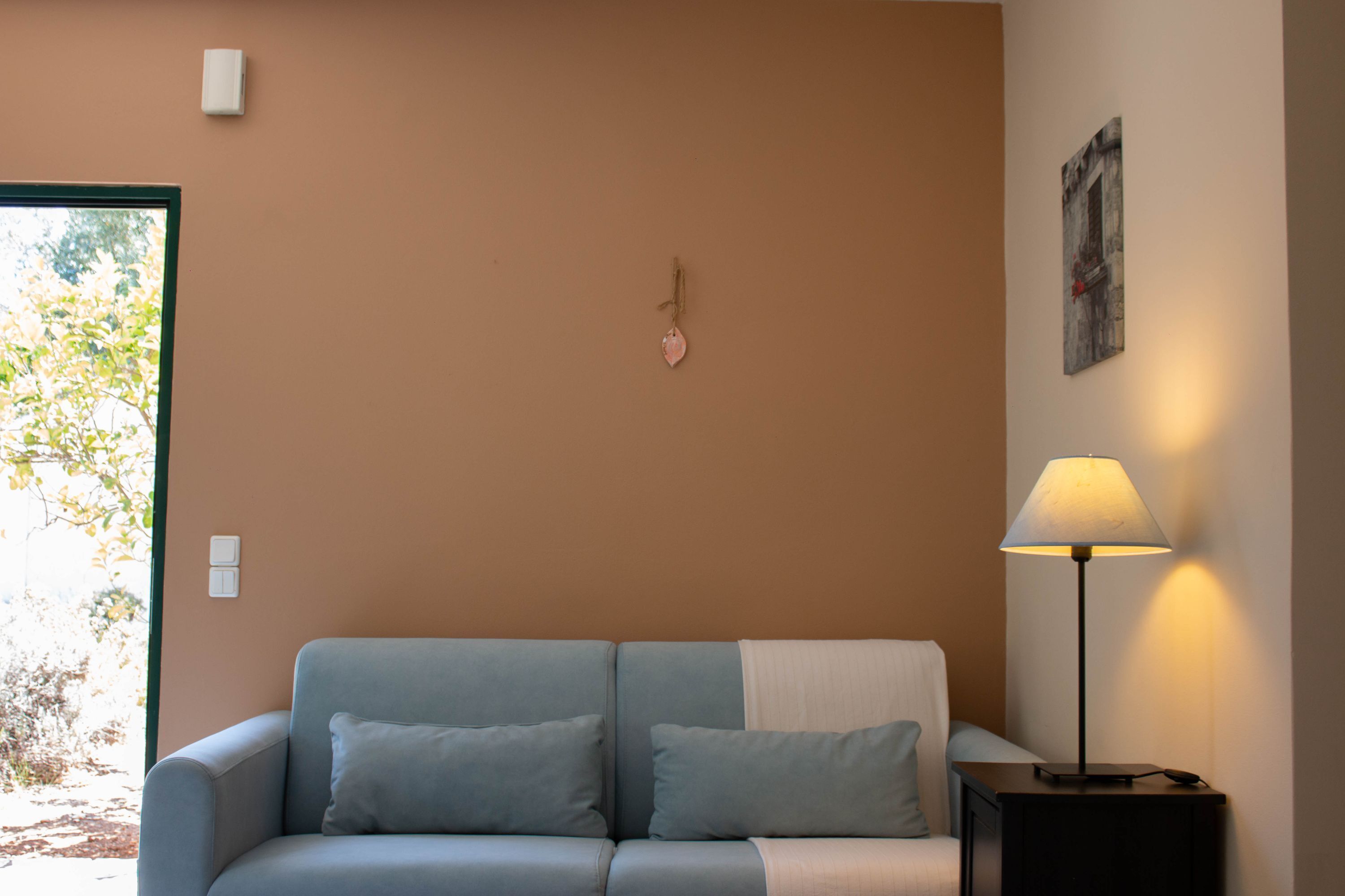 Una habitación con sofá, lámpara y un adorno en la pared.