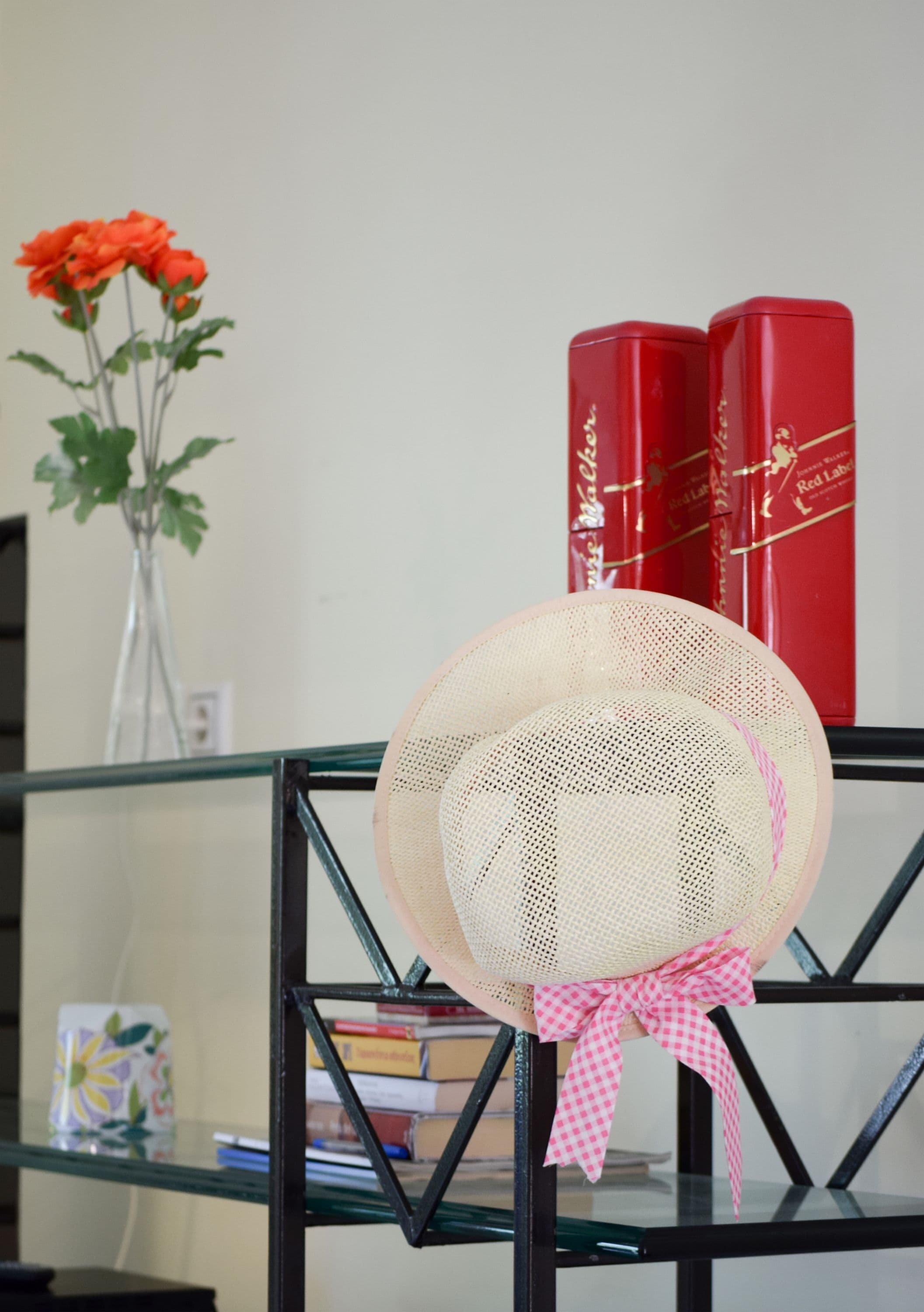 A bookshelf with two red books and a vase with red flowers.