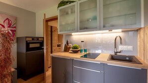 A modern kitchen with grey cabinets, a stainless steel refrigerator, and a wooden countertop. - Alpine's Nest studio apartment with mountain views (Kirchberg in Tirol)