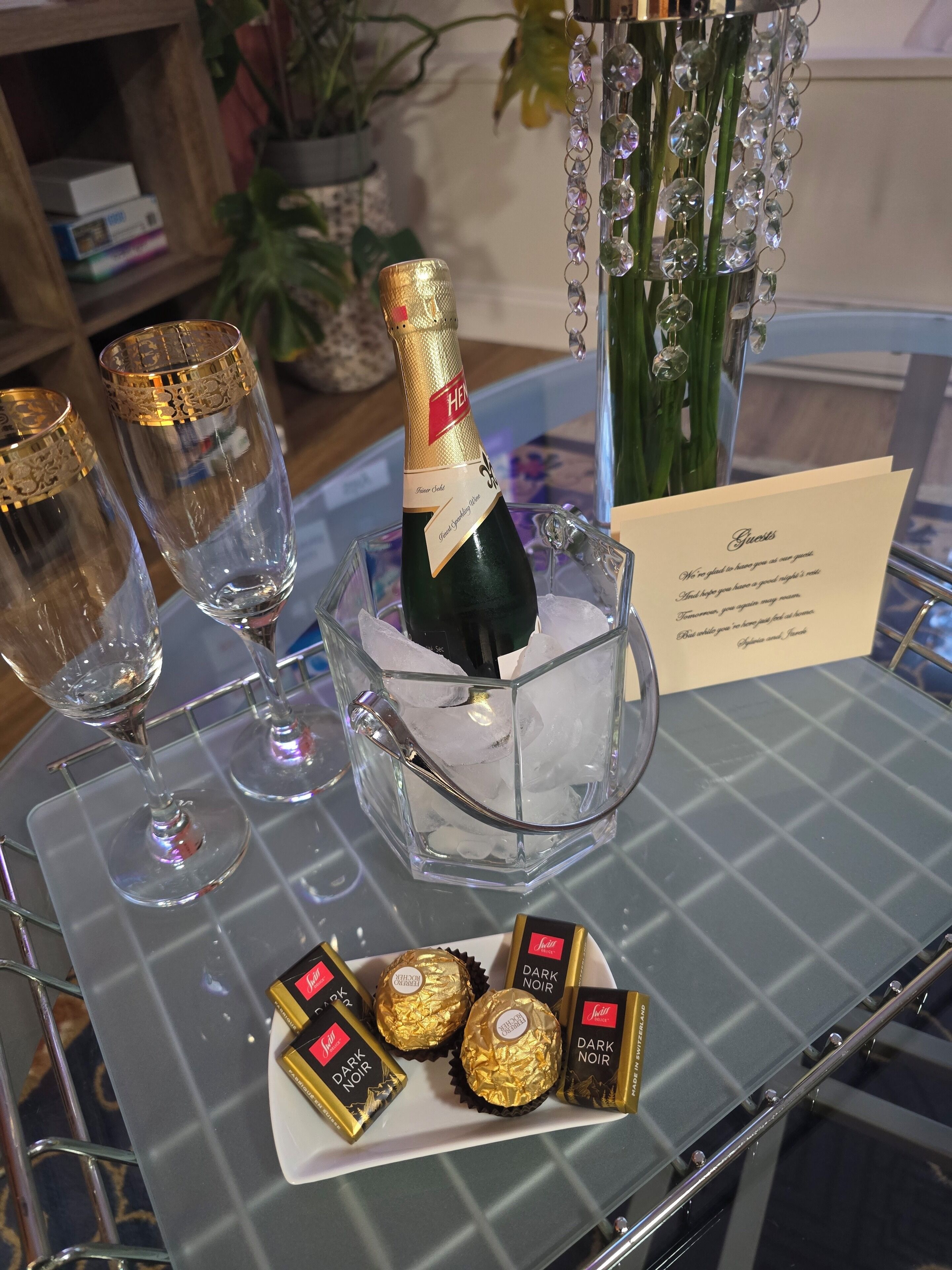 Un coin bar avec une bouteille de champagne dans un seau à glace, deux coupes à champagne vides et une assiette de chocolats.