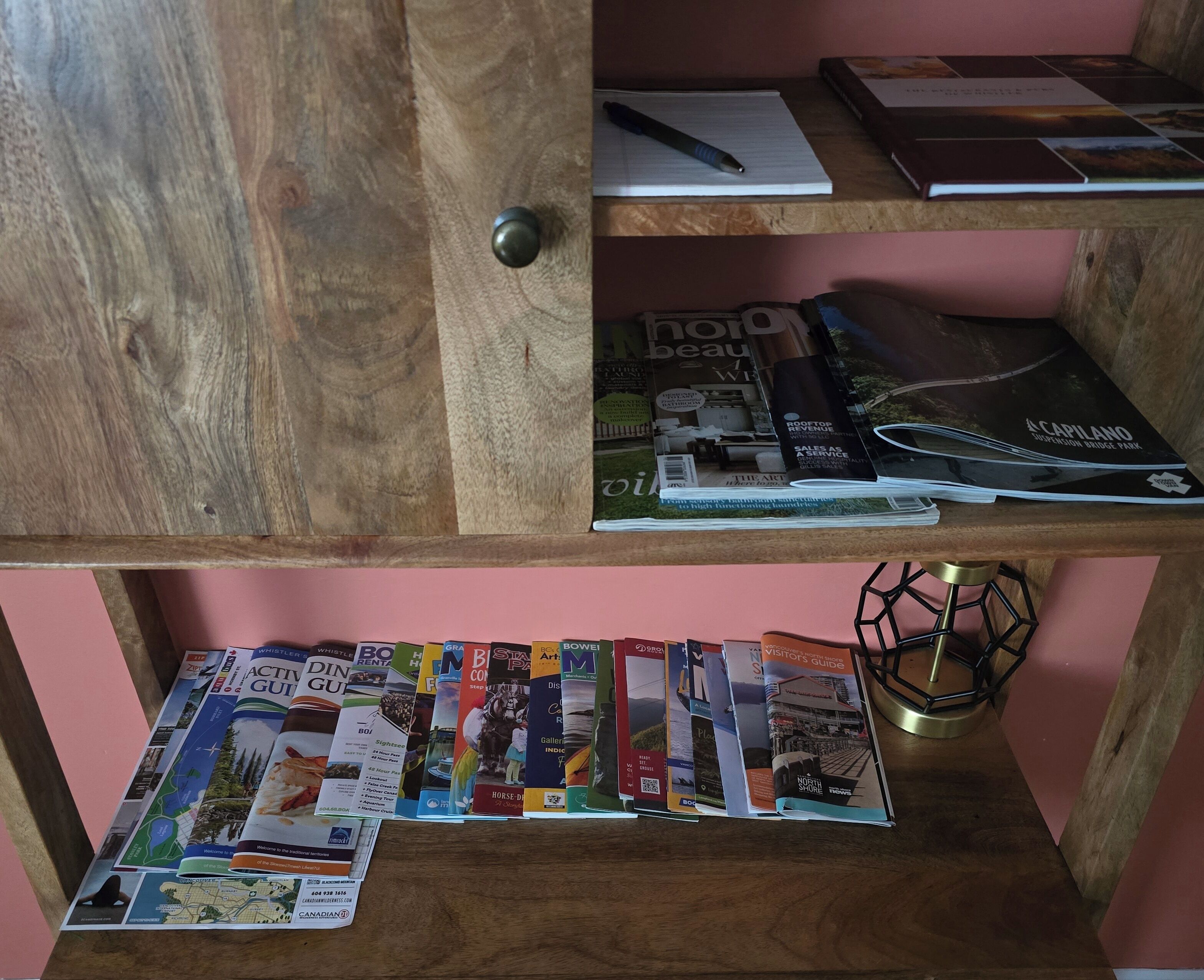 Estante de madeira com diversos folhetos de viagens e uma revista.