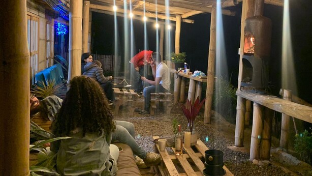 An outdoor seating area with bamboo pillars, a wood-burning stove, and hanging lights. - San Vicente (San Vicente)